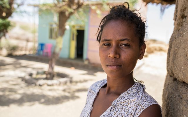 Woman looking at the camera while leaning against the wall